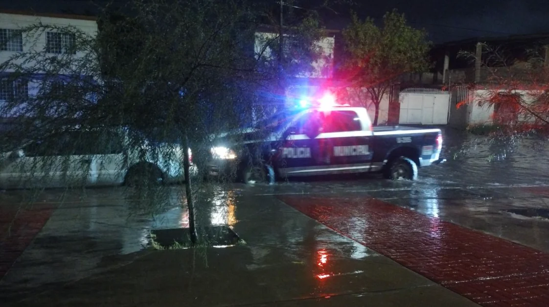 Vehículos circulan por una avenida encharcada tras las lluvias en Ciudad Juárez