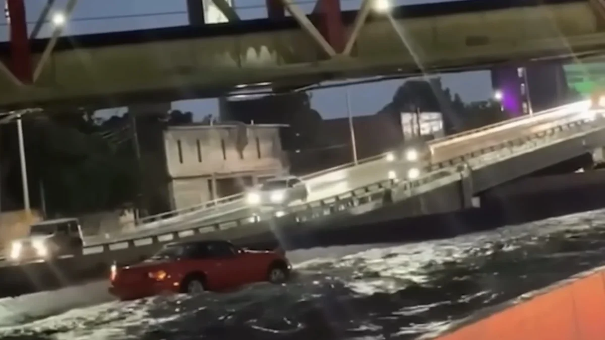 Mazda MX-5 rojo circula entre una corriente de agua en una vialidad atribuida a Chihuahua capital