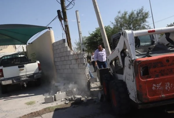Trabajadores municipales demuelen una barda que obstruía una banqueta en la colonia La Cuesta