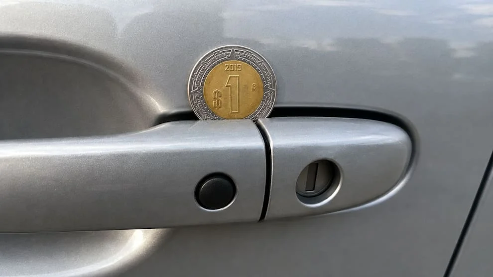 Moneda colocada en la manija de la puerta de un automóvil