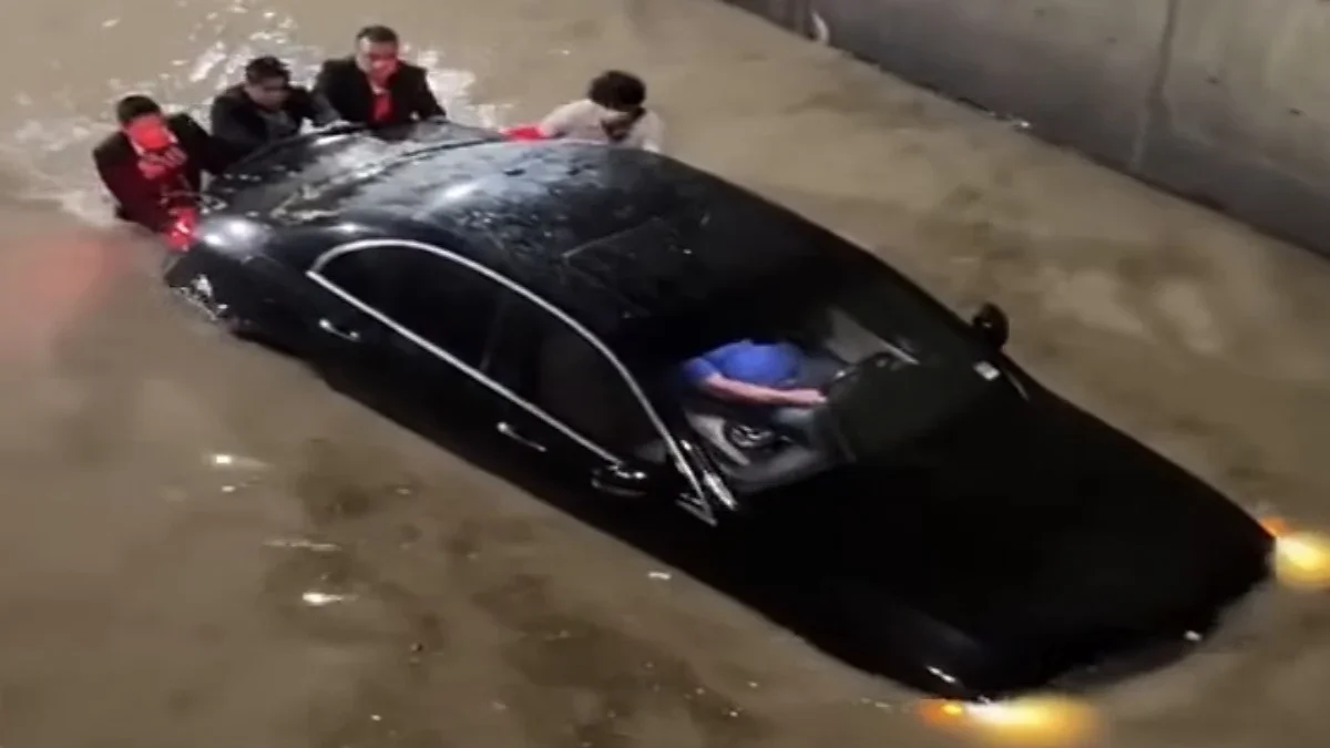 Personas junto a un automóvil negro atrapado en una inundación en Las Torres y Sorgo
