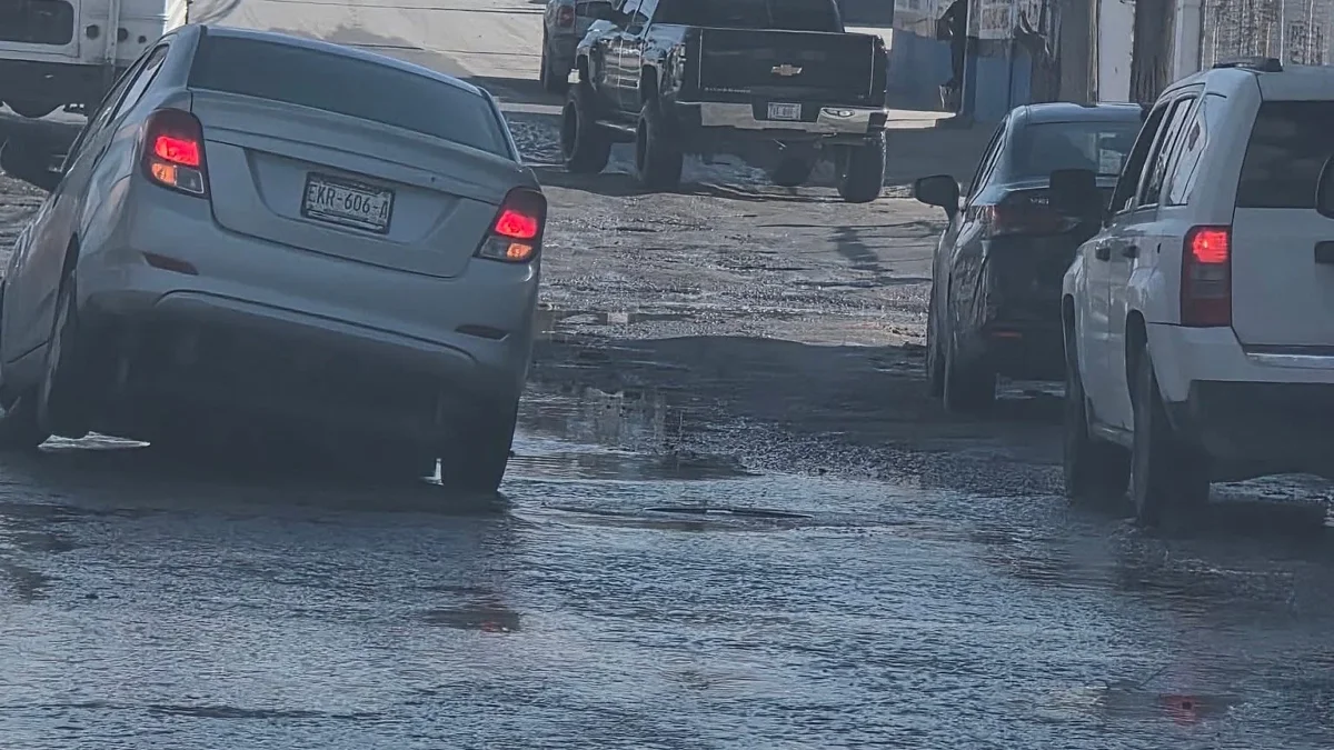 Automóvil circula entre baches y agua acumulada en la avenida de los Aztecas de Ciudad Juárez