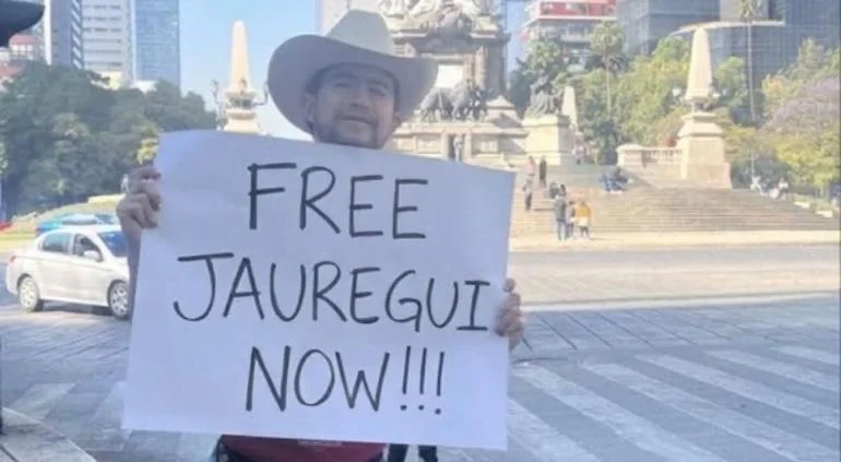 Alán Nevarez sostiene en Paseo de la Reforma una cartulina para pedir la libertad de César Jáuregui