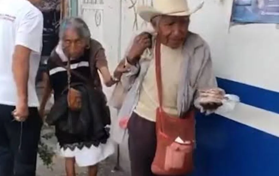 ¡En las buenas y en las malas! Abuelito guía de la mano a su esposa ciega mientras venden cacahuates