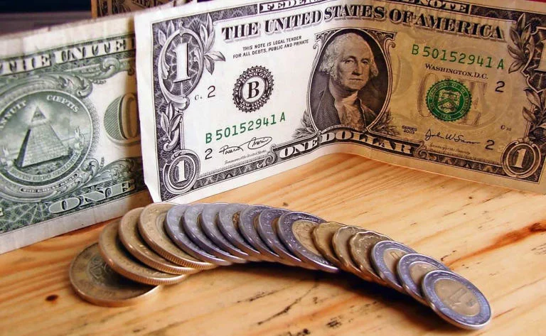 Billetes de pesos mexicanos y dólares ante posible recorte de tasa de Banxico