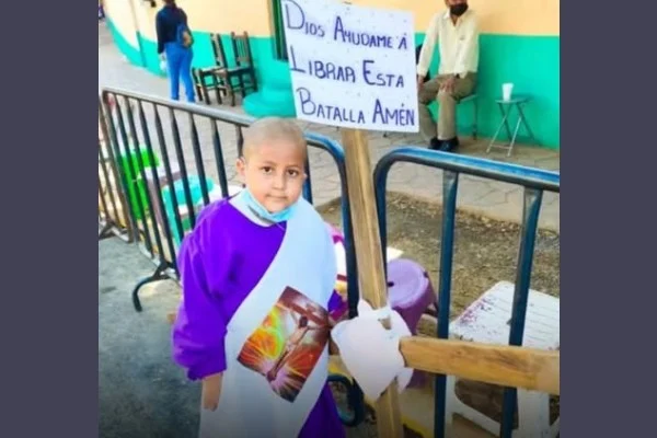 Niño con leucemia carga una cruz de madera durante una representación religiosa